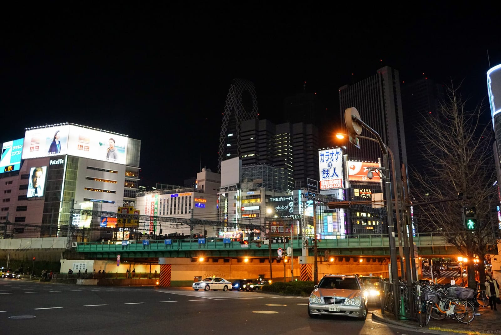夜の新宿の街並み。ネオンの看板と高架の線路。