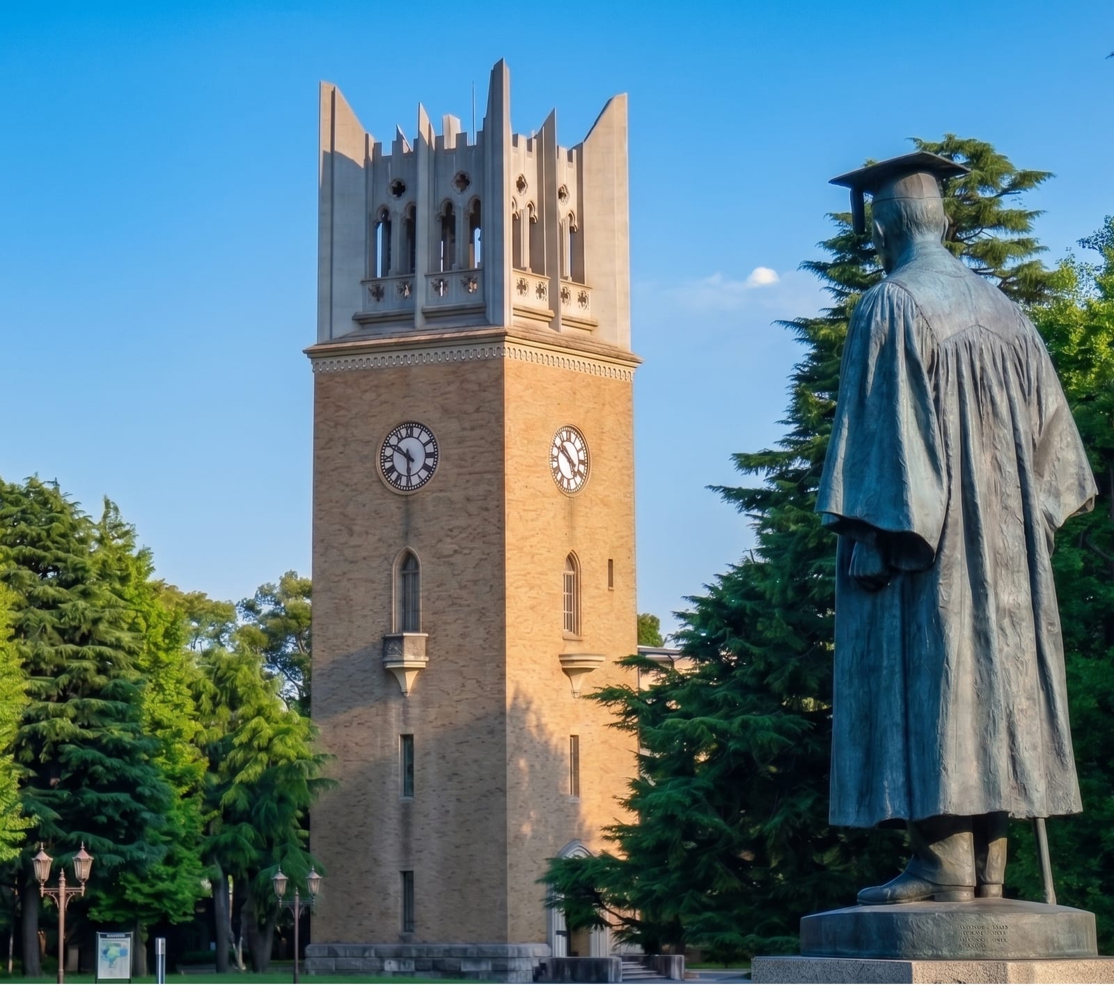 早稲田大学の大隈講堂の時計塔と、その手前に立つ学位服姿の大隈重信像。